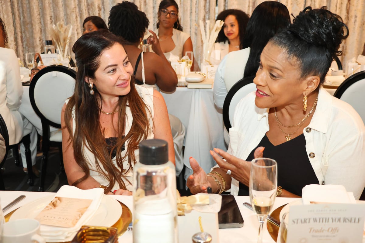 Two women in thoughtful conversation over dinner at She Takes Her Seat